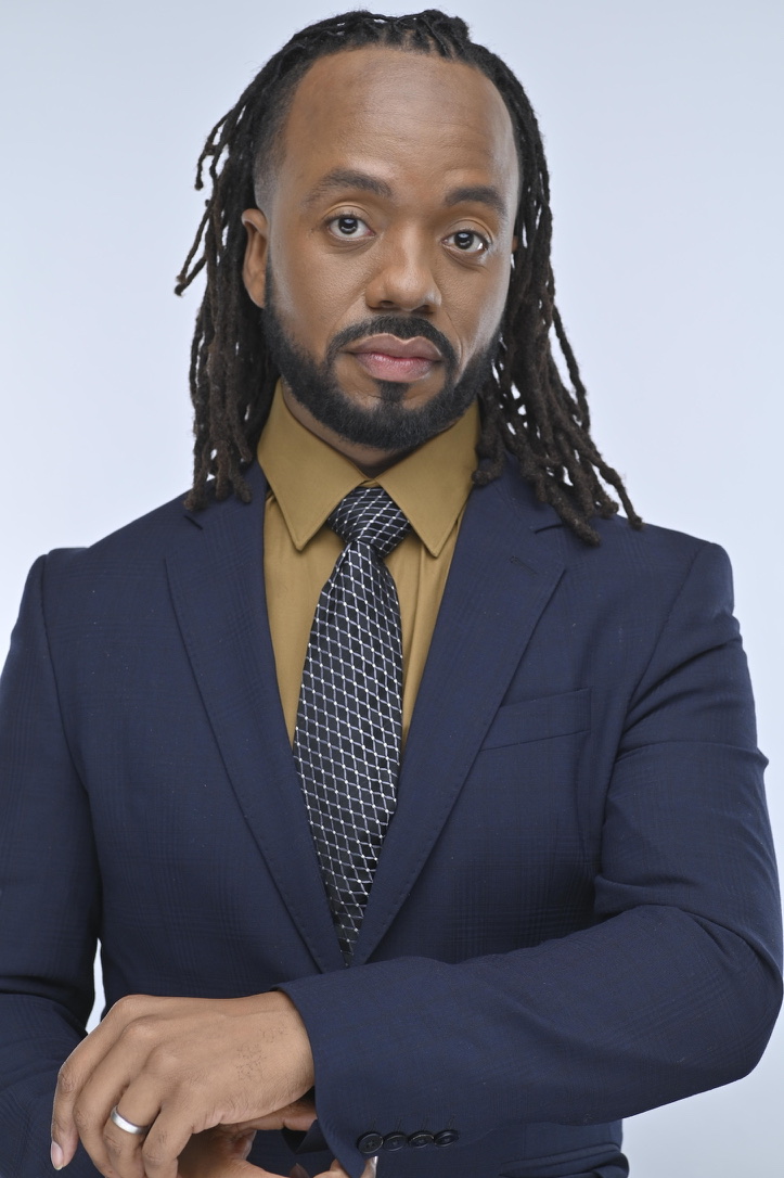 Portrait of Elijah Cathey-Li in a navy suit, mustard shirt and patterned tie